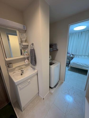 東京にあるさくら旅館高円寺北千利休102号室の洗面台、鏡、トイレ付きのバスルーム