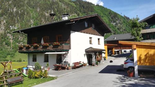 a white building with a black roof and a mountain at Kleintierhof Seidl-Eder in Rauris