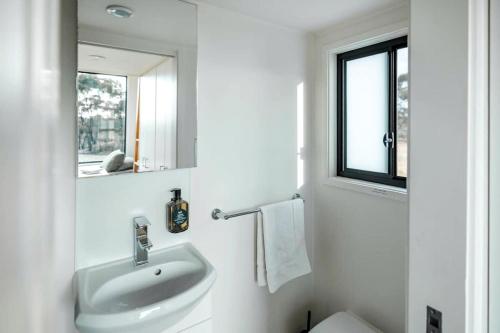 a white bathroom with a sink and a mirror at Lovely Tiny House with Barbecue in Maiden Gully, Victoria in Woodvale