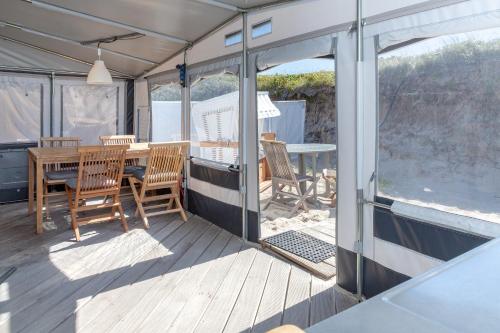 a screened in porch with a table and chairs at Wohnwagenvermietung Hörnum / Sylt in Hörnum