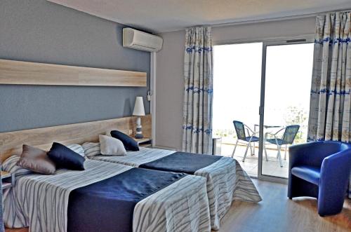 1 dormitorio con 1 cama, 1 silla y balcón en Logis Hotel Solhotel, en Banyuls-sur-Mer