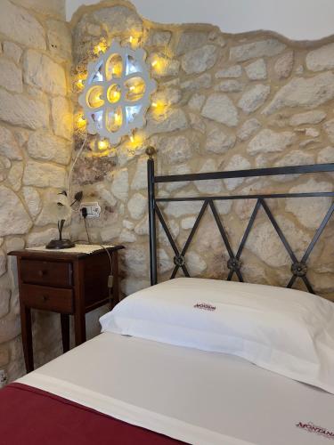 a bedroom with a bed and a stone wall at Masseria Casina Montana in Corigliano dʼOtranto