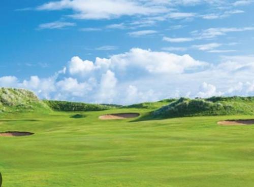 a green golf course with hills in the background at Atlantic Coast Lodge in Spanish Point