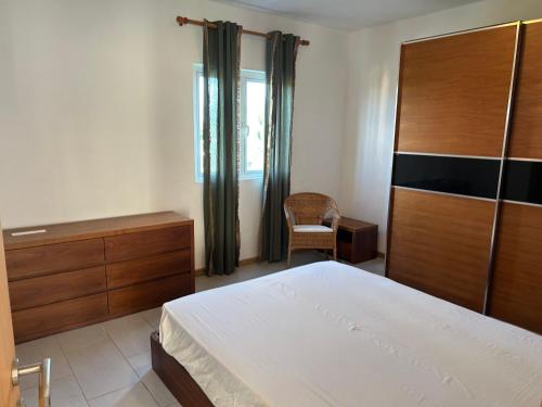 een slaapkamer met een bed, een dressoir en een stoel bij Moon Flower, Pereybere in Grand Baie