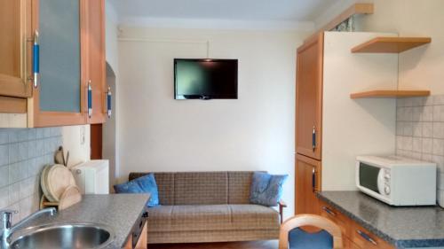 a kitchen with a couch and a tv on the wall at Gästehaus Golker in Bad Gastein