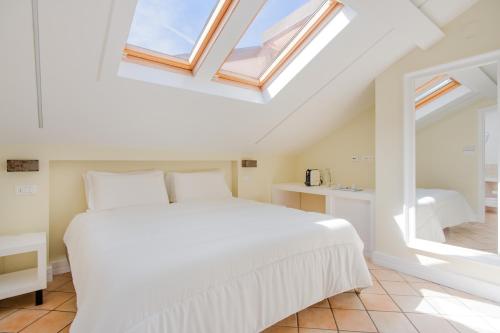 ein Schlafzimmer mit einem weißen Bett und einem Dachfenster in der Unterkunft Palazzo Gargiulo Luxury in Sorrent