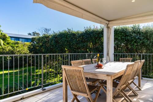 a wooden table and chairs on a patio with a fence at Seaview - Mangawhai Heads Holiday Home in Mangawhai