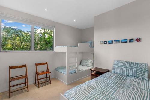a bedroom with a bunk bed and two chairs at Seaview - Mangawhai Heads Holiday Home in Mangawhai