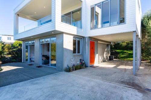 a large white house with a red door at Seaview - Mangawhai Heads Holiday Home in Mangawhai