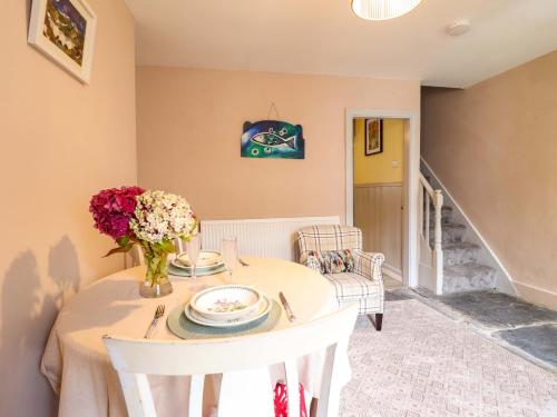 a dining room with a table with flowers on it at Bwthyn Bach in Porthmadog