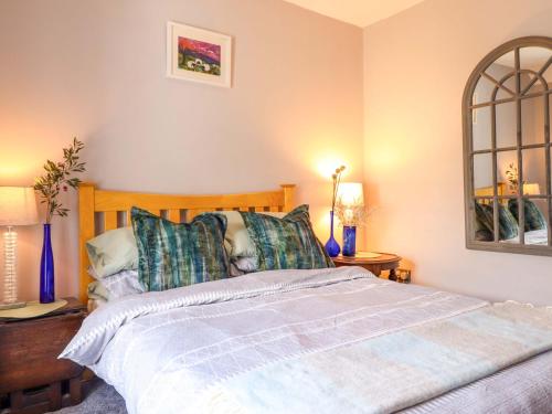 a bedroom with a large bed with blue pillows at Bwthyn Bach in Porthmadog