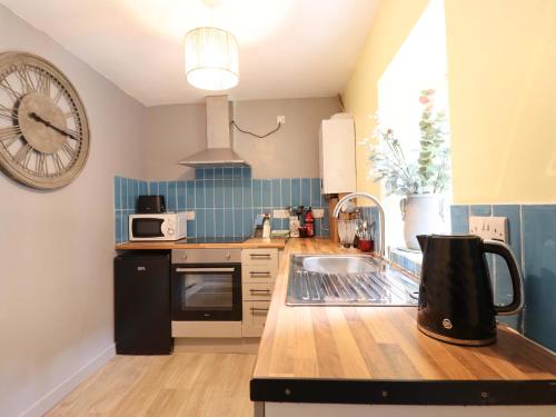 a kitchen with a sink and a clock on the wall at Bwthyn Bach in Porthmadog
