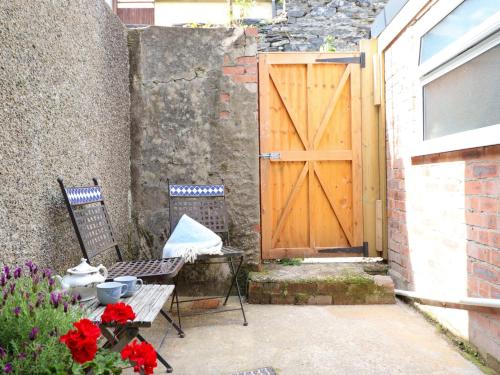 a wooden door with two chairs and a table with flowers at Bwthyn Bach in Porthmadog