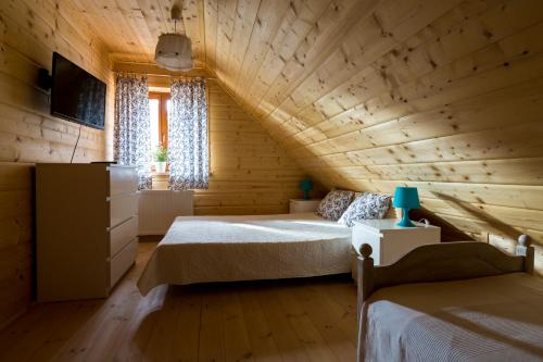 a bedroom with two beds in a log cabin at Willa Pasym in Pasym