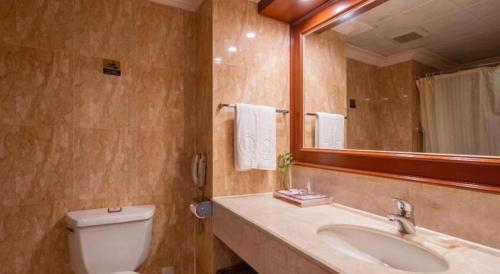 a bathroom with a toilet and a sink and a mirror at Quanzhou Hotel in Quanzhou