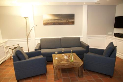 uma sala de estar com um sofá e duas cadeiras e uma mesa em Tag am Meer Sylt II em Westerland