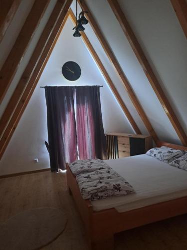 a attic room with a bed and a window at Vikendica Una-Bakšaiš in Bihać
