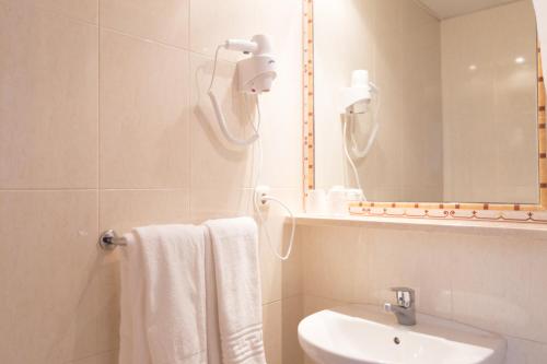 a white bathroom with a sink and a mirror at Hotel Mediterráneo by Croma in Estepona