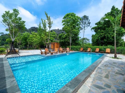 a pool at a resort with chairs and trees at Chilling Homestay - Hotel in Vũ Lâm