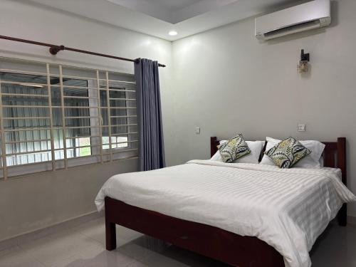 a bedroom with a bed with white sheets and a window at ColYve Siem Reap in Phum Pobos