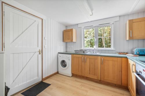 a kitchen with a white door and a washing machine at Peaceful lodge in New Forest with garden in Breamore