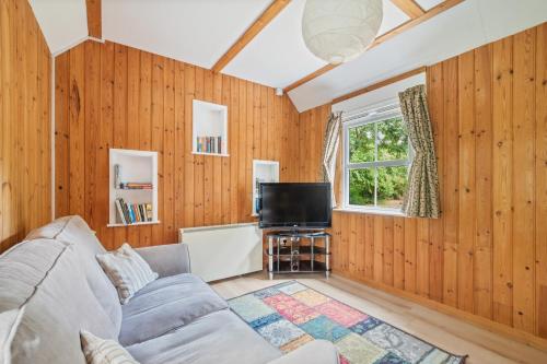 a living room with a couch and a tv at Peaceful lodge in New Forest with garden in Breamore
