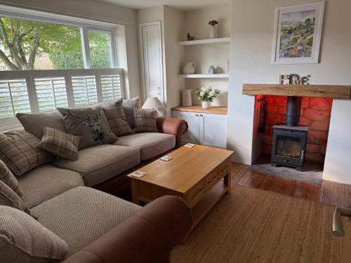 ein Wohnzimmer mit Couch und Kamin in der Unterkunft Maple Cottage in Bourton on the Water