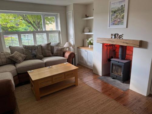 ein Wohnzimmer mit einem Sofa und einem Holzofen in der Unterkunft Maple Cottage in Bourton on the Water