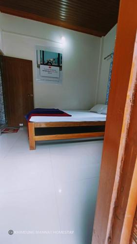a small room with a bed and a mirror at Khimdung Mannat Homestay in Mangpu