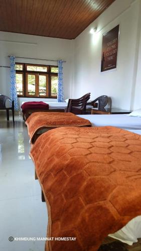 a row of beds in a room with chairs at Khimdung Mannat Homestay in Mangpu