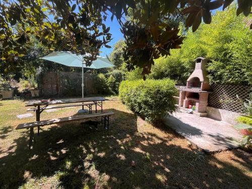 a picnic table with an umbrella and a grill at Nel giardino segreto vista giardino in San Giorgio a Liri
