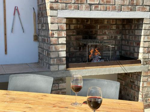 two glasses of wine sitting on a table with a fireplace at Poseidon Beachfront Holiday Home in Swakopmund