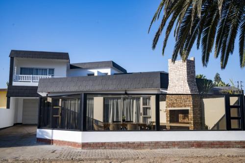 a house with large glass doors and a palm tree at Poseidon Beachfront Holiday Home in Swakopmund