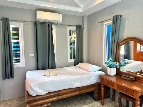 Un dormitorio con una cama, un espejo y una mesa. en Sky Blue Bungalows, en Phra Ae beach