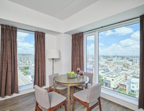 a dining room with a table and chairs and large windows at Luxury Apartments by Hyatus at Central Philly in Philadelphia