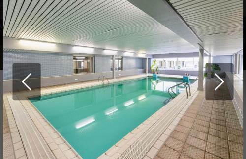 a large swimming pool with a large blue pool at Studio terrasse in Middelkerke