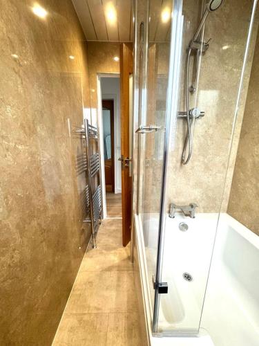 a bathroom with a shower and a tub and a sink at Newtown Hideaway in Boʼness