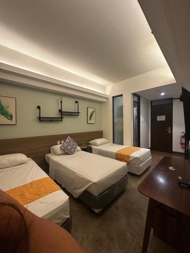 a hotel room with three beds and a table at The Greenhive Hotel in Ibaan
