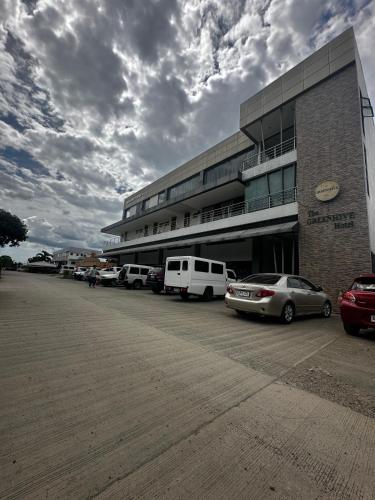 a parking lot with cars parked in front of a building at The Greenhive Hotel in Ibaan
