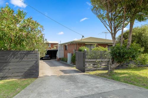 a house with a fence in front of a driveway at Charming Cape Wooli Home in Cape Woolamai