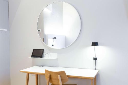 a mirror on a wall above a desk with a table and chairs at Scandic Helsinki Aviapolis in Vantaa