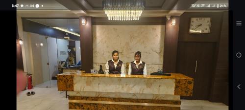 two people sitting at a desk in a lobby at The Moris palace hotel in Rajkot