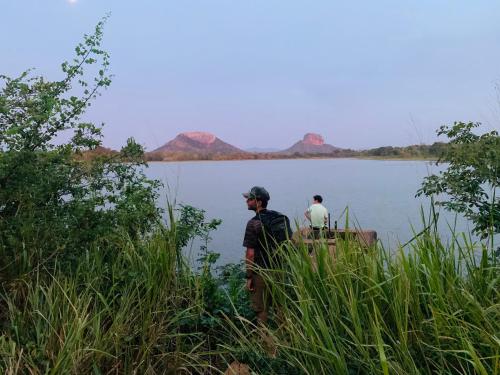 two men standing on the edge of a lake at Sigiri Village Vibe Hostel in Sigiriya