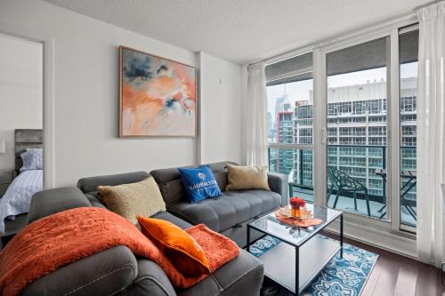 a living room with a couch and a large window at Autumnaly Whisper 2 BR & DEN in the Heart of the City in Toronto