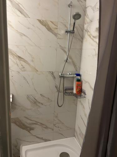 a bathroom with a shower with a white marble wall at Vlinder 2pers studio in Utrecht