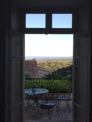 an open door to a balcony with a table and chairs at Auberge De Tourrettes in Tourrettes-sur-Loup