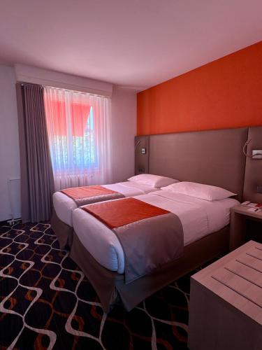 a hotel room with two beds and a window at Hotel Eden in Geneva