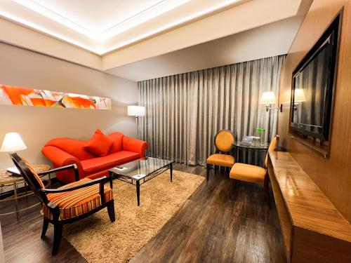 a living room with a red couch and a tv at The Bellevue Manila in Manila