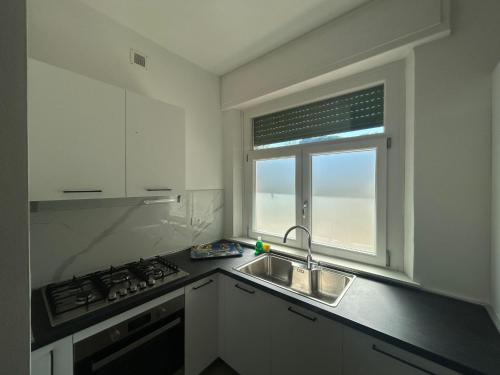a kitchen with a sink and a stove and a window at Pineta Apartament in Tirrenia