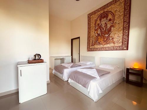 two beds in a room with a painting on the wall at The Wind Farm in Dahab